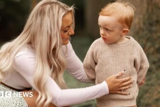 A mother kneels next to her toddler son