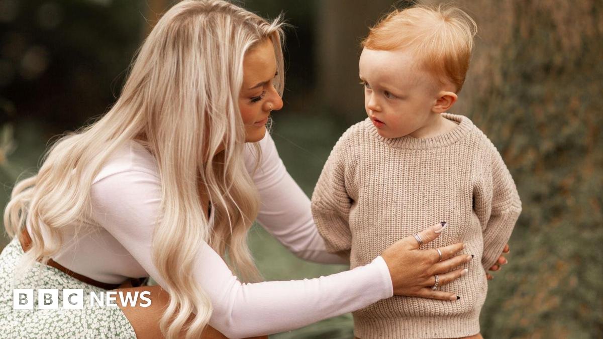 A mother kneels next to her toddler son